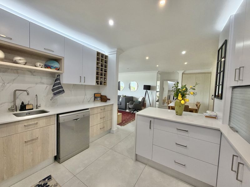Modern open-plan kitchen featuring sleek cabinetry, stone countertops, integrated appliances, and high-quality finishes, seamlessly flowing into the adjacent living and dining areas.
