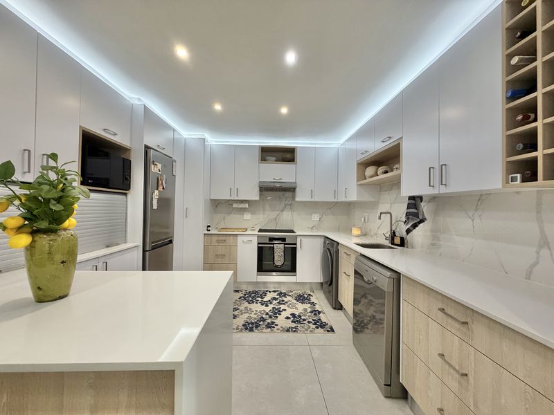 Modern, well-appointed kitchen featuring sleek cabinetry, stone countertops, integrated appliances, and elegant LED strip lighting, offering a clean and functional culinary space.
