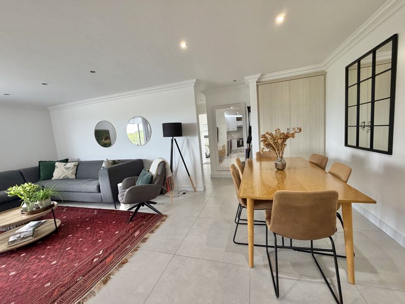 Spacious open-plan living and dining area featuring modern tiled flooring, recessed lighting, and neutral finishes, creating a bright and inviting atmosphere.