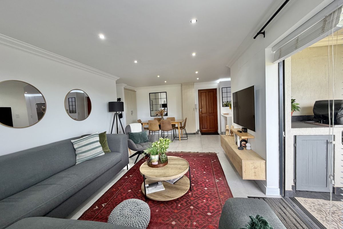 Spacious open-plan living and dining area featuring tiled floors, recessed lighting, and seamless access to an outdoor balcony through large sliding glass doors.