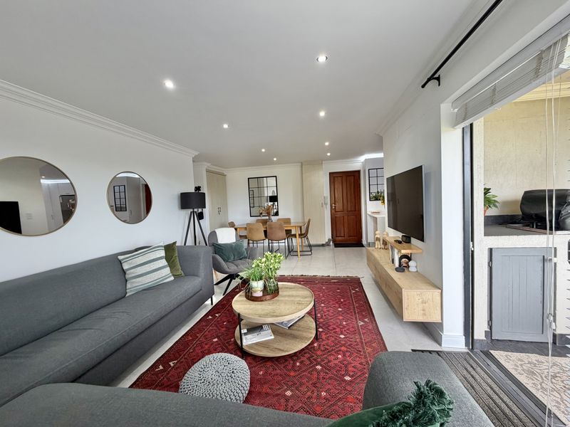 Spacious open-plan living and dining area featuring tiled floors, recessed lighting, and seamless access to an outdoor balcony through large sliding glass doors.