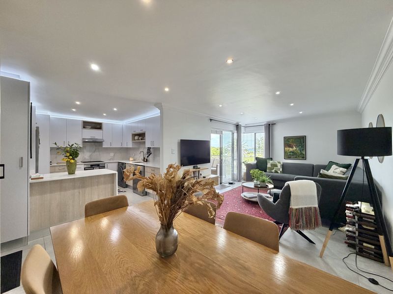 Modern open-plan living area featuring a contemporary kitchen with stone countertops, integrated appliances, and seamless flow to a bright lounge with sliding door access.