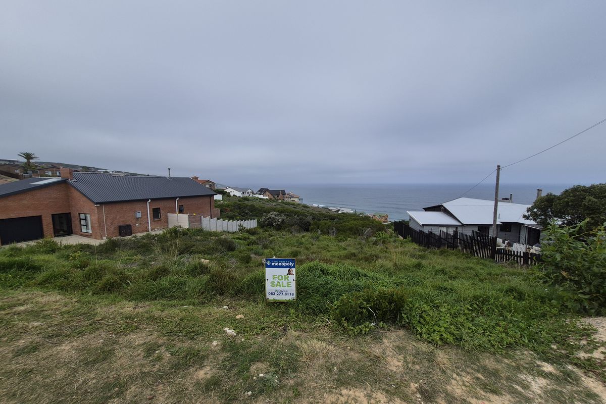 A vacant residential plot featuring a scenic coastal view, situated in a developed neighborhood with surrounding residential properties.