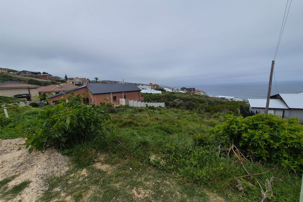 A wide-angle view of a coastal residential area, showcasing the surrounding neighborhood and ocean horizon from the vacant land plot.