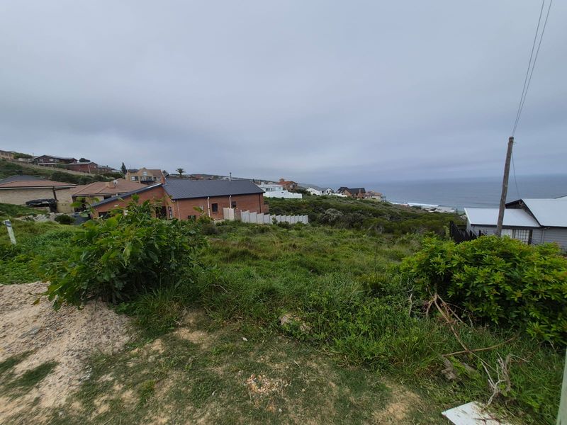 A wide-angle view of a coastal residential area, showcasing the surrounding neighborhood and ocean horizon from the vacant land plot.