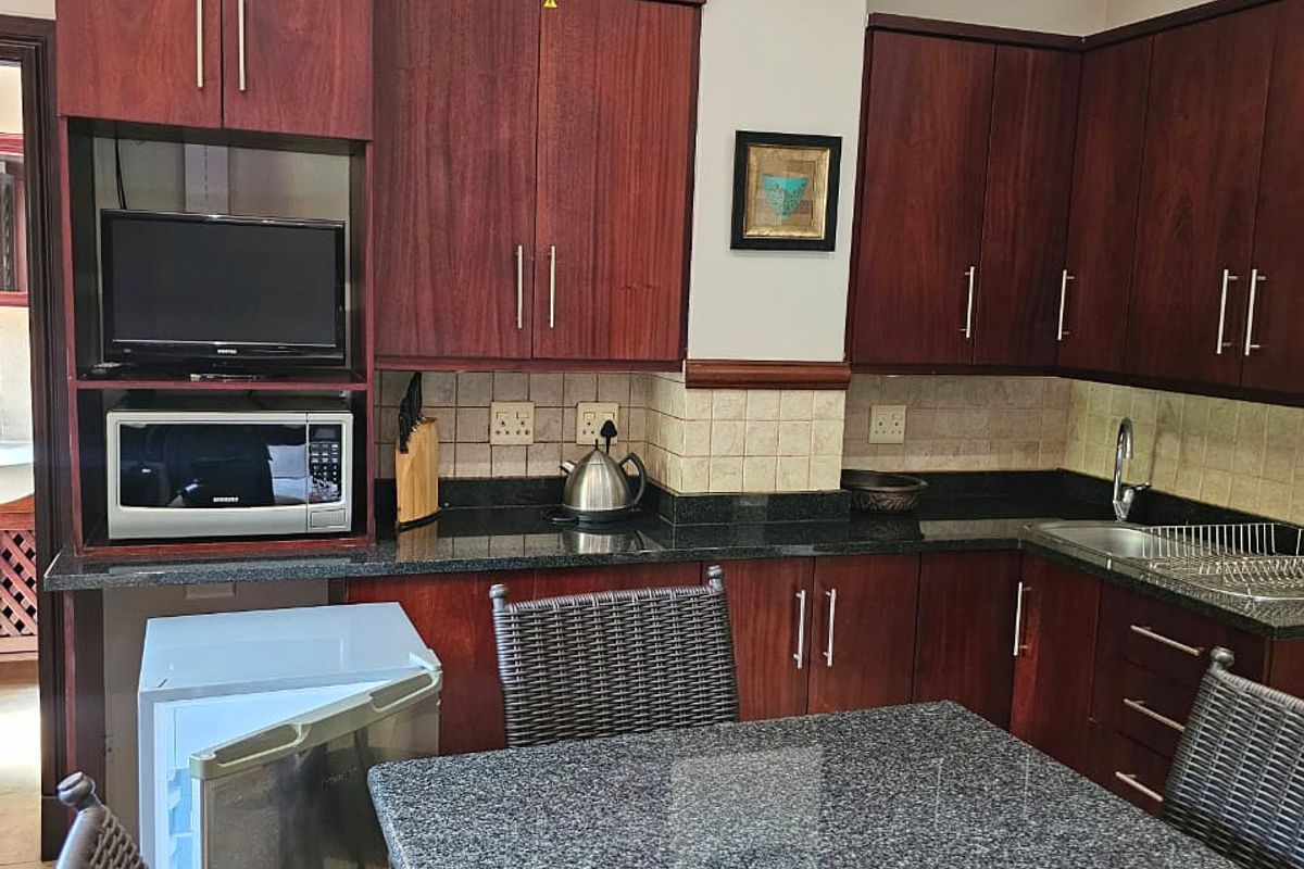 A functional kitchen featuring dark wood cabinetry, granite countertops, a tiled backsplash, and integrated microwave, offering a classic and well-maintained workspace.
