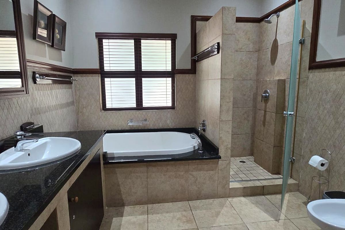 A well-appointed bathroom featuring a double vanity with granite countertops, a built-in bathtub, a separate walk-in shower, and a bidet.