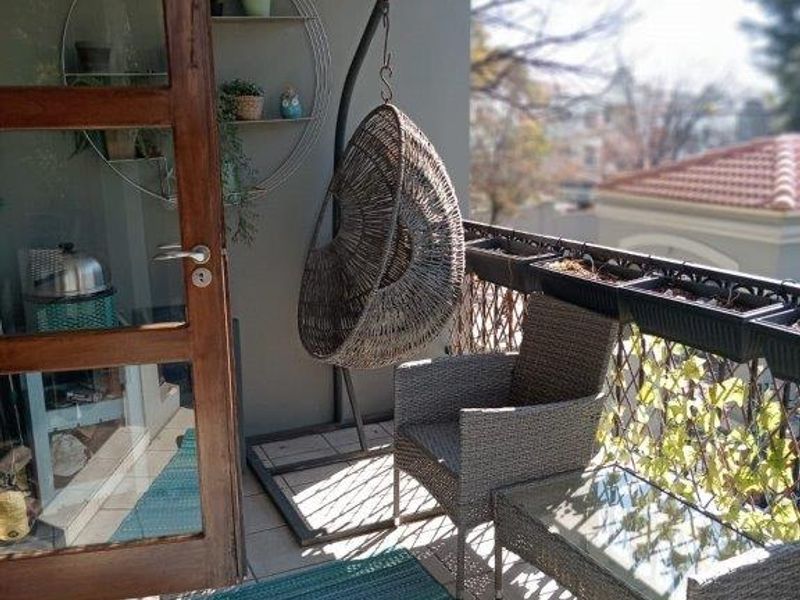 A covered balcony featuring tiled flooring, a metal balustrade, and a timber-framed glass door providing access to the interior.