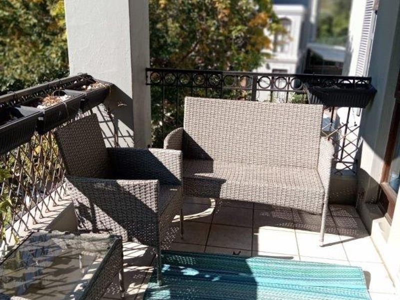 A covered balcony featuring tiled flooring, a sturdy concrete pillar, and decorative wrought iron railings, offering a pleasant outdoor space.