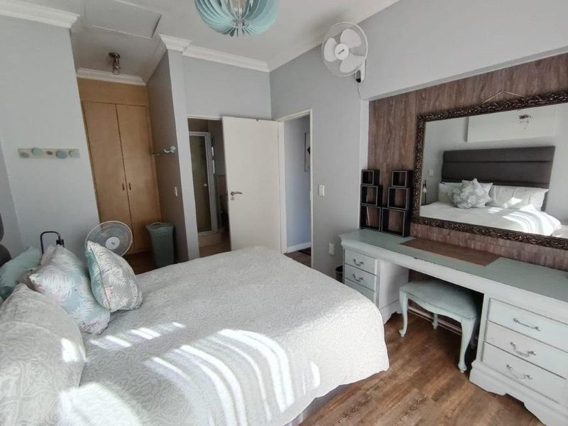 A well-lit bedroom featuring laminate flooring, built-in cupboards, and direct access to an en-suite bathroom.