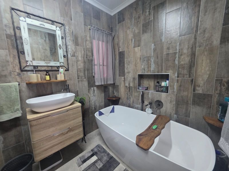 Modern bathroom featuring a freestanding bathtub, vessel sink on a wood-finish vanity, and stylish wood-look wall tiling with a convenient recessed storage niche.