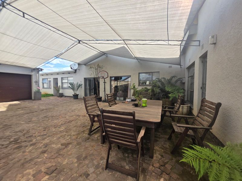 Spacious paved courtyard area featuring a large shade cloth canopy, providing a versatile outdoor entertainment space with direct access to the home.