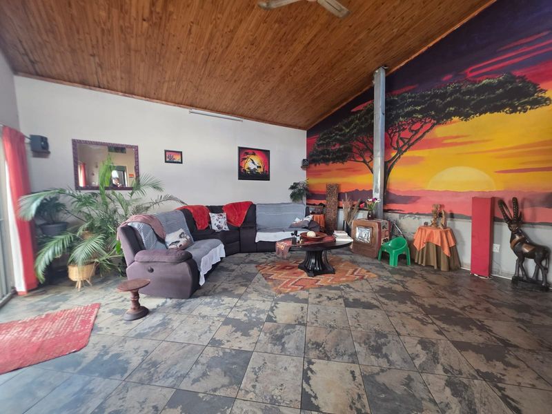 Spacious living room featuring a wood-paneled ceiling, tiled flooring, and a built-in fireplace, offering a unique aesthetic with a large feature wall mural.