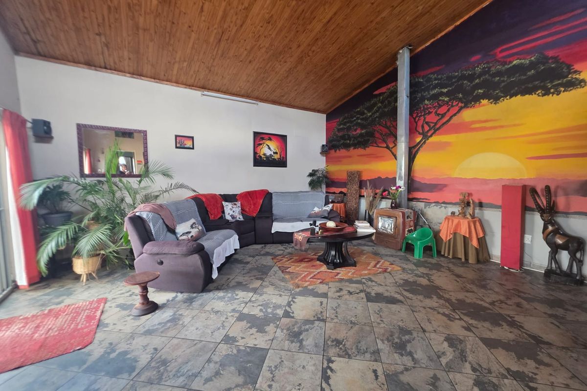 Spacious living room featuring a wood-paneled ceiling, tiled flooring, and a built-in fireplace, offering a unique aesthetic with a large feature wall mural.