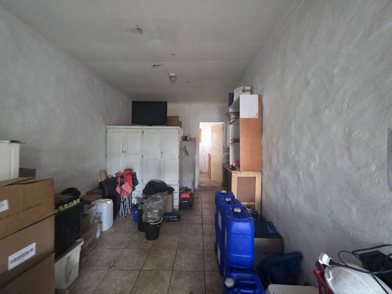 A utility or storage room featuring tiled flooring and basic ceiling lighting, currently used for storage with visible signs of wear on walls and ceiling.