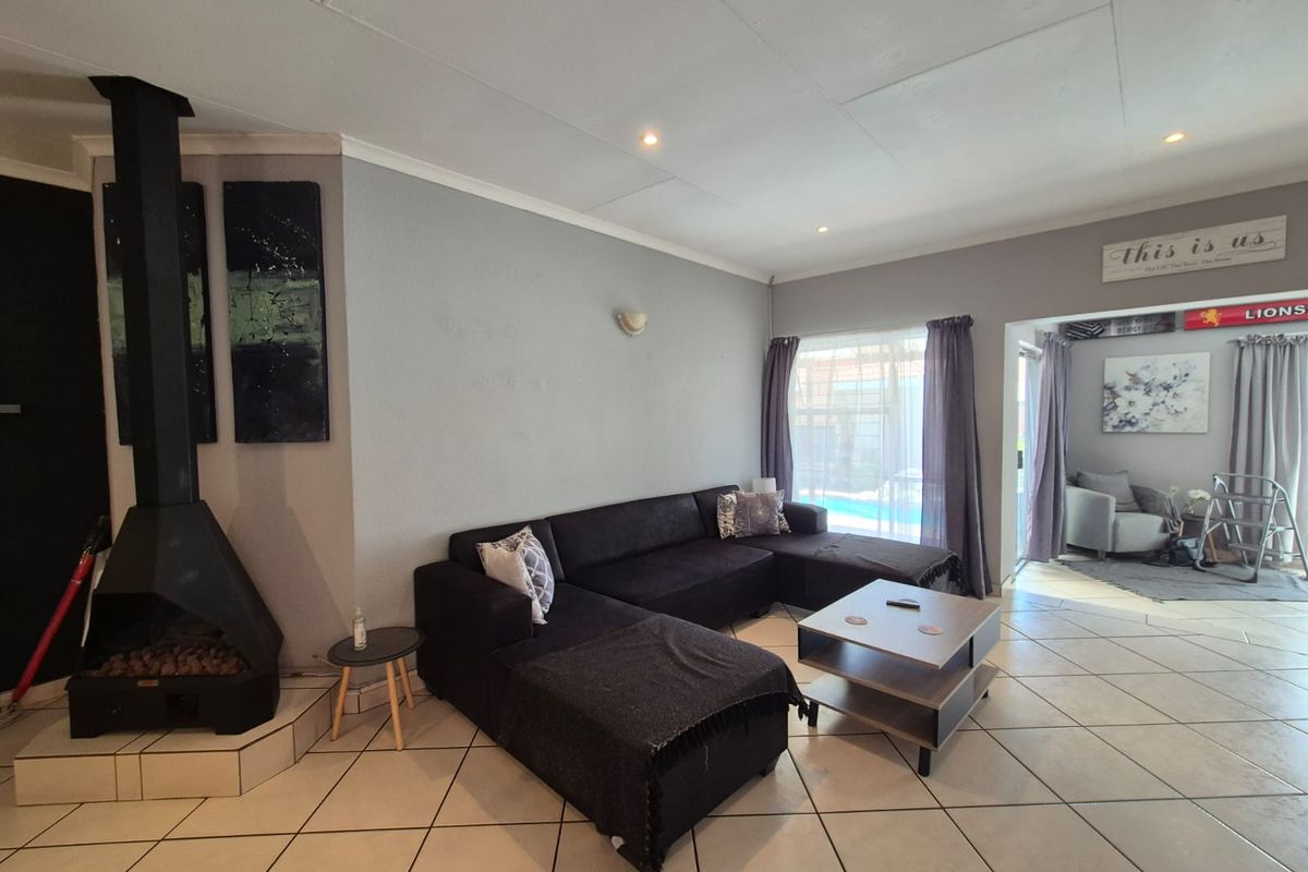 Spacious living room featuring tiled flooring, a prominent freestanding fireplace, and direct access to the outdoor area through sliding doors.