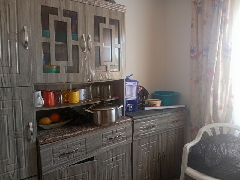 A kitchen area featuring wood-grain laminate cabinetry and countertops, showing signs of wear and requiring minor maintenance to cabinet hardware.