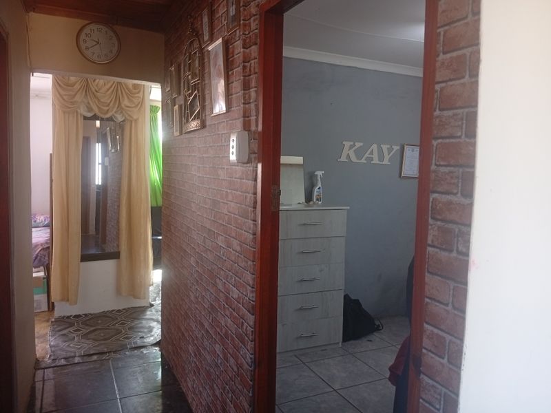 A hallway featuring brick-style wall cladding and tiled flooring, providing access to adjacent rooms within the home.