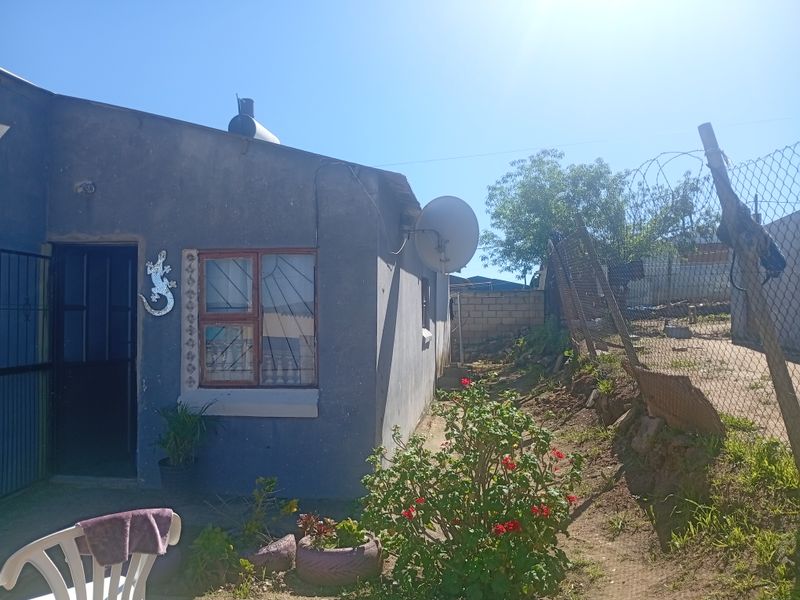 Rear exterior view of the property featuring a security gate, burglar bars, and perimeter chain link fencing.