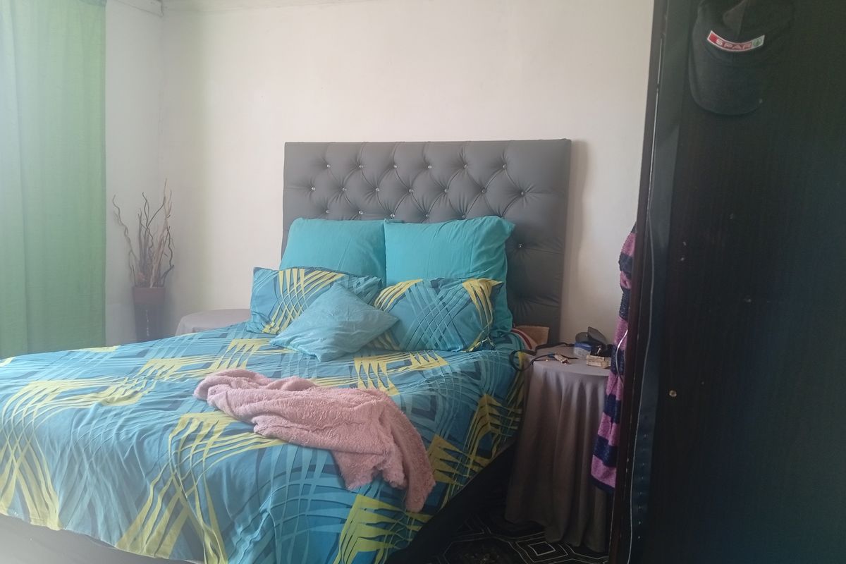 A standard bedroom featuring a tufted headboard and tiled flooring.