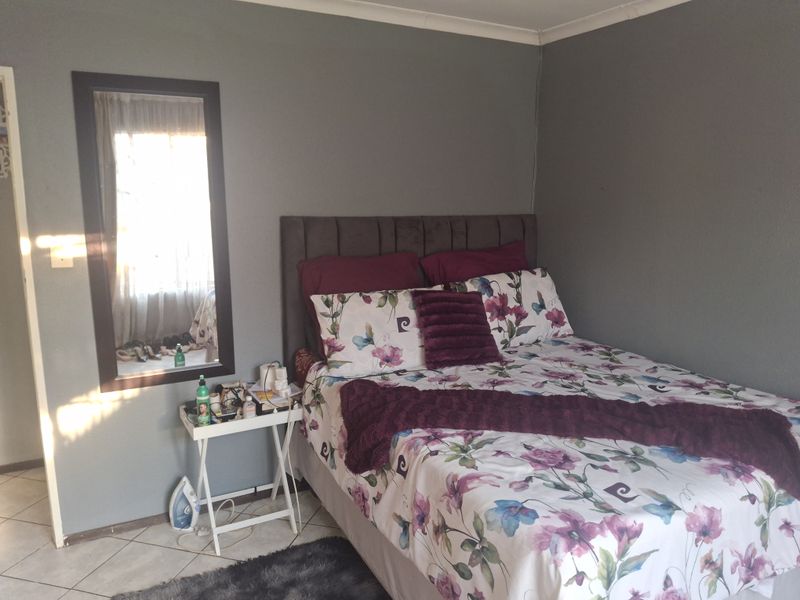 A bedroom featuring tiled flooring and neutral grey walls, providing a functional space with natural light.