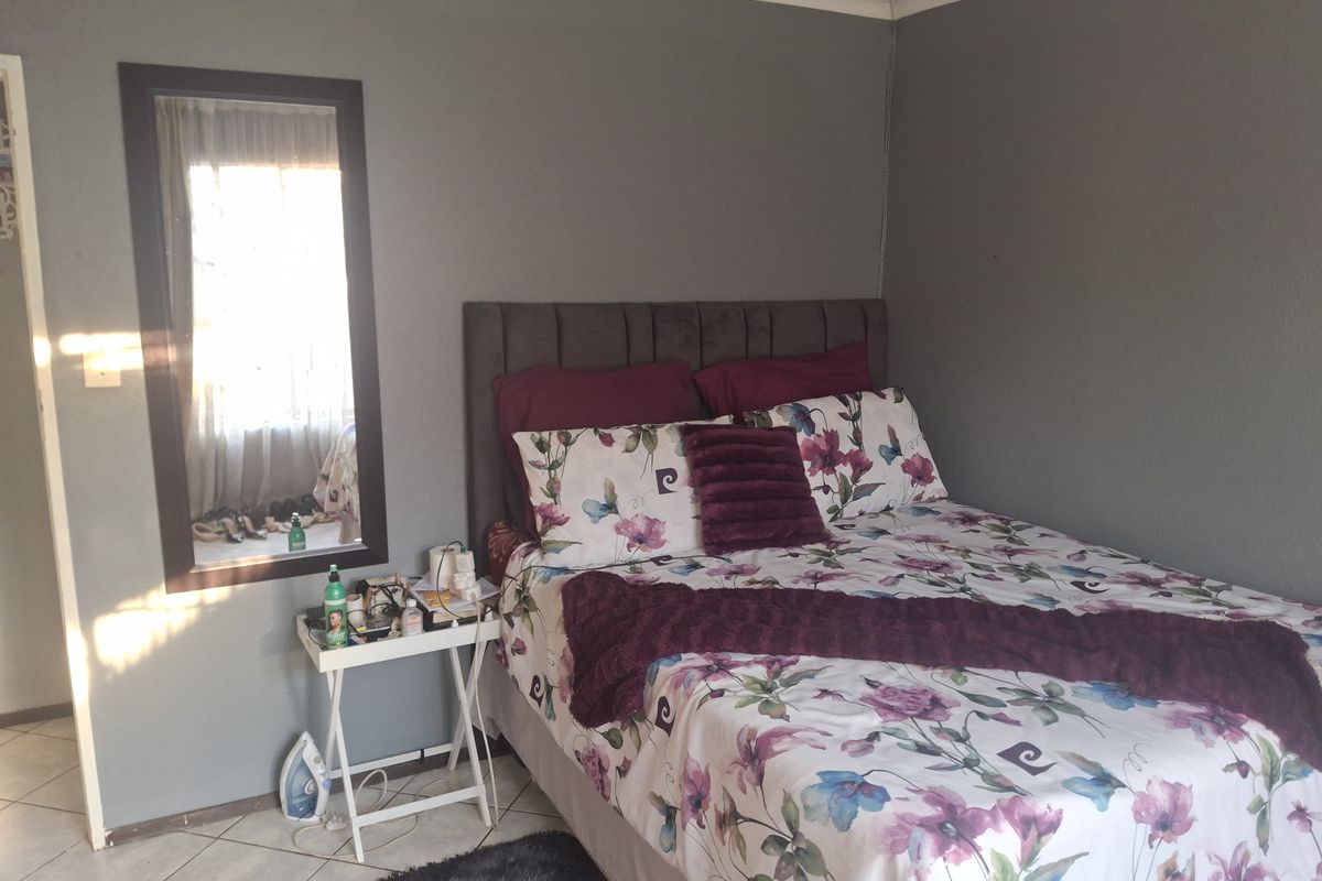 A bedroom featuring tiled flooring and neutral grey walls, providing a functional space with natural light.