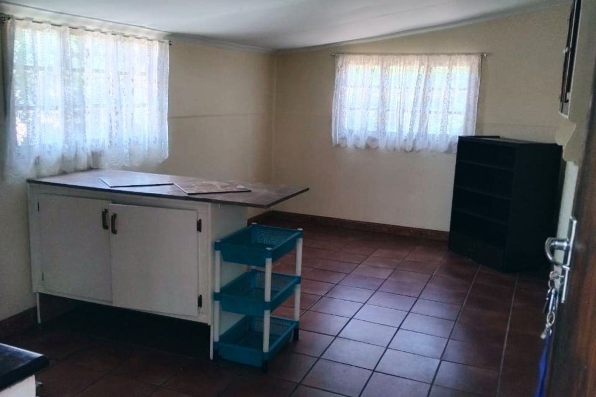 A functional kitchen space featuring tiled flooring, built-in cabinetry, and natural light from two windows, offering potential for modernization and layout optimization.