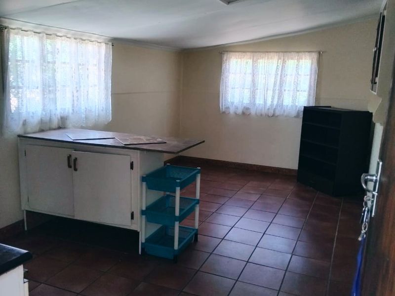 A functional kitchen space featuring tiled flooring, built-in cabinetry, and natural light from two windows, offering potential for modernization and layout optimization.