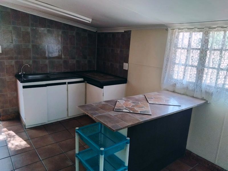 A functional kitchen area featuring built-in cabinetry, tiled countertops, and a tiled splashback, offering a practical layout ready for modernization.