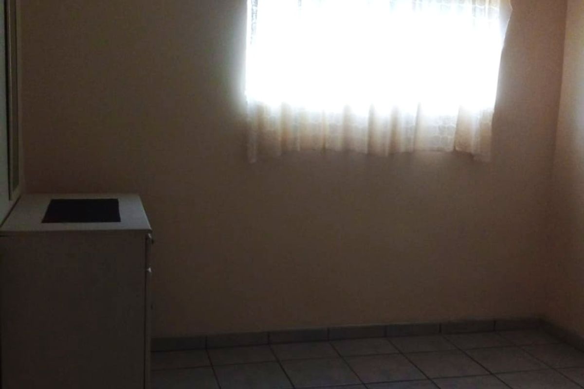 A simple, empty bedroom featuring neutral wall paint, tiled flooring, and a coved ceiling, offering a blank canvas for personalization.