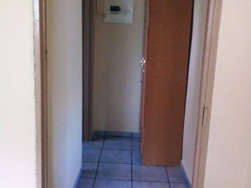 A functional hallway featuring tiled flooring and a wall-mounted electrical distribution board.