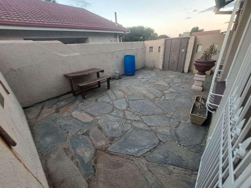 A private rear courtyard area featuring flagstone paving and enclosed by boundary walls with a secure metal gate access.