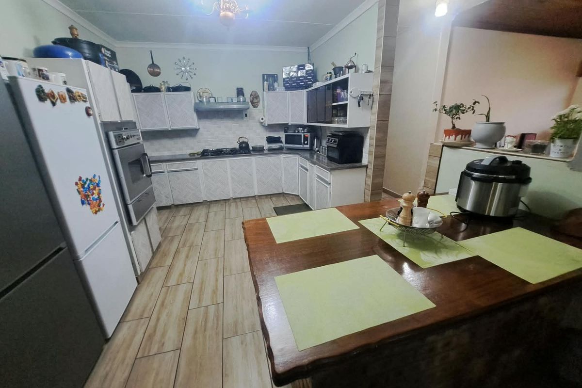A functional kitchen featuring built-in cabinetry, a gas hob, an integrated oven, and tiled flooring, offering a practical layout for daily cooking.