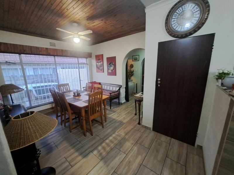 Dining room featuring a timber-clad ceiling, ceiling fan, tiled flooring, and an arched doorway leading to adjacent living spaces.