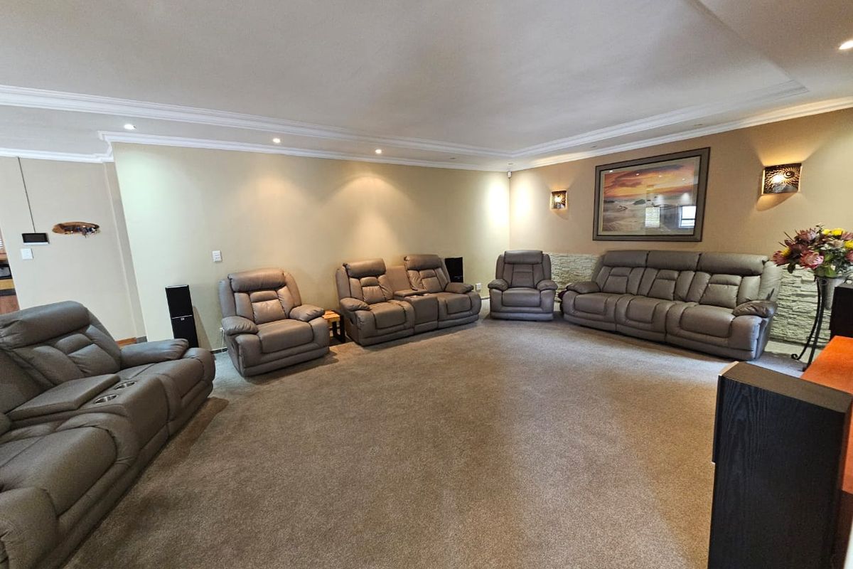 Spacious living room featuring a coved ceiling with recessed downlights and a decorative stone feature wall.