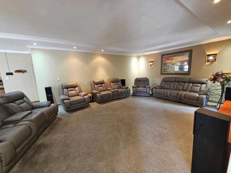 Spacious living room featuring a coved ceiling with recessed downlights and a decorative stone feature wall.
