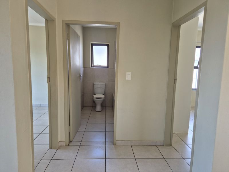 A neutral hallway providing access to multiple rooms, featuring tiled flooring and standard internal door frames.