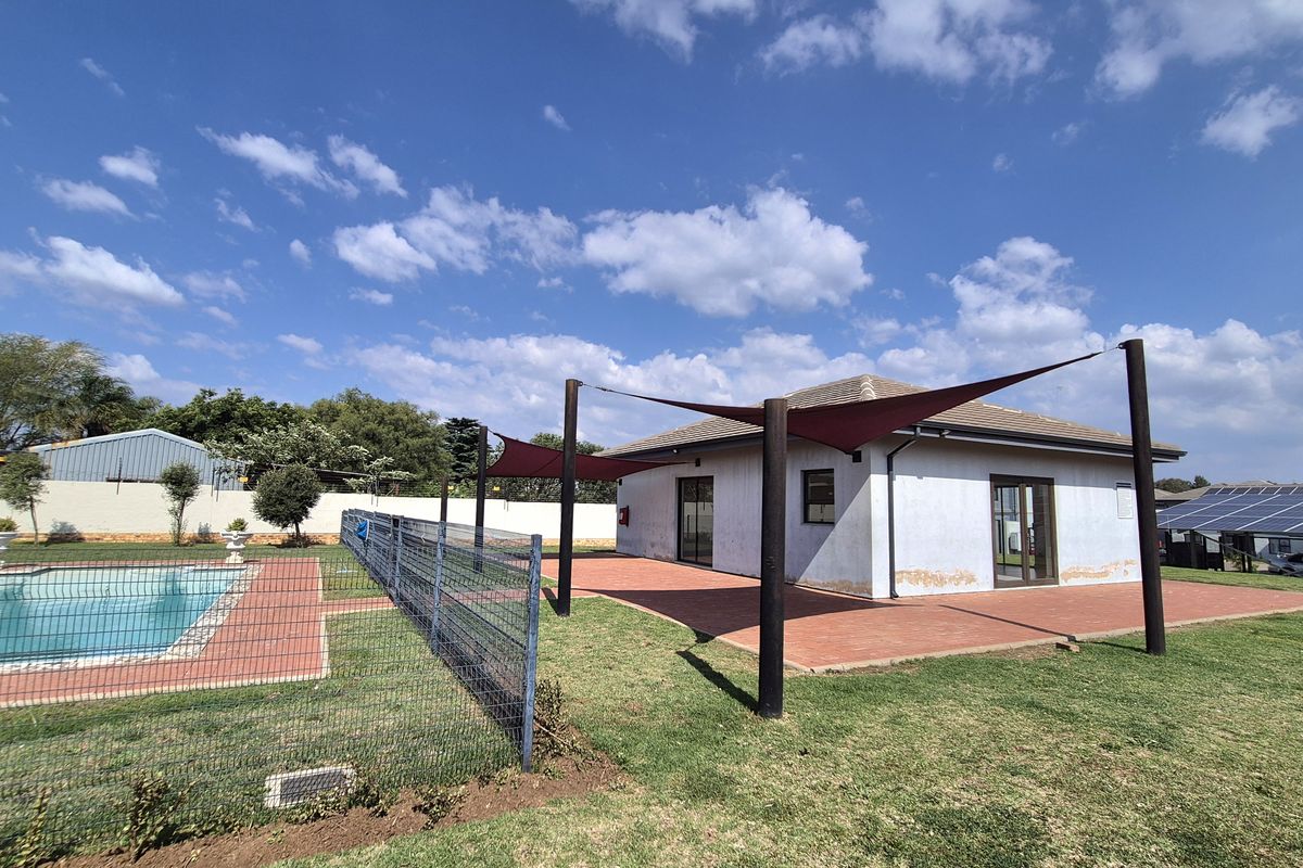 Rear exterior view of the property featuring a tiled patio, shade sail structure, and a swimming pool with perimeter fencing.