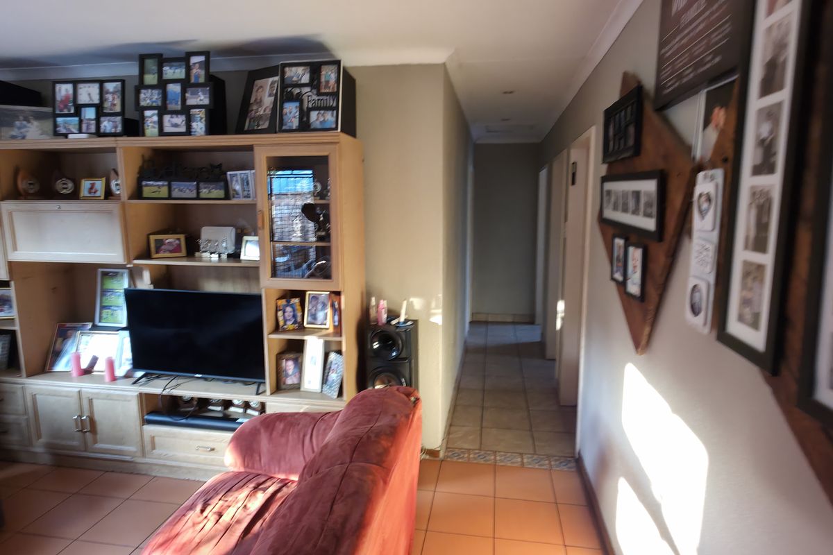 A living room featuring tiled flooring, built-in cabinetry, and access to a hallway, providing a functional and lived-in space.