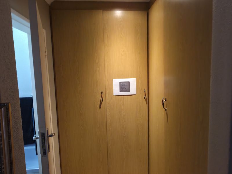 A hallway area featuring built-in wooden cupboards and wall-mounted utility controls.