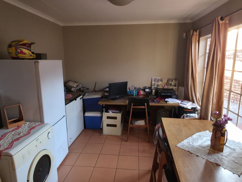 A functional kitchen area featuring tiled flooring and natural light from a large window, offering potential for modernization and improved layout.