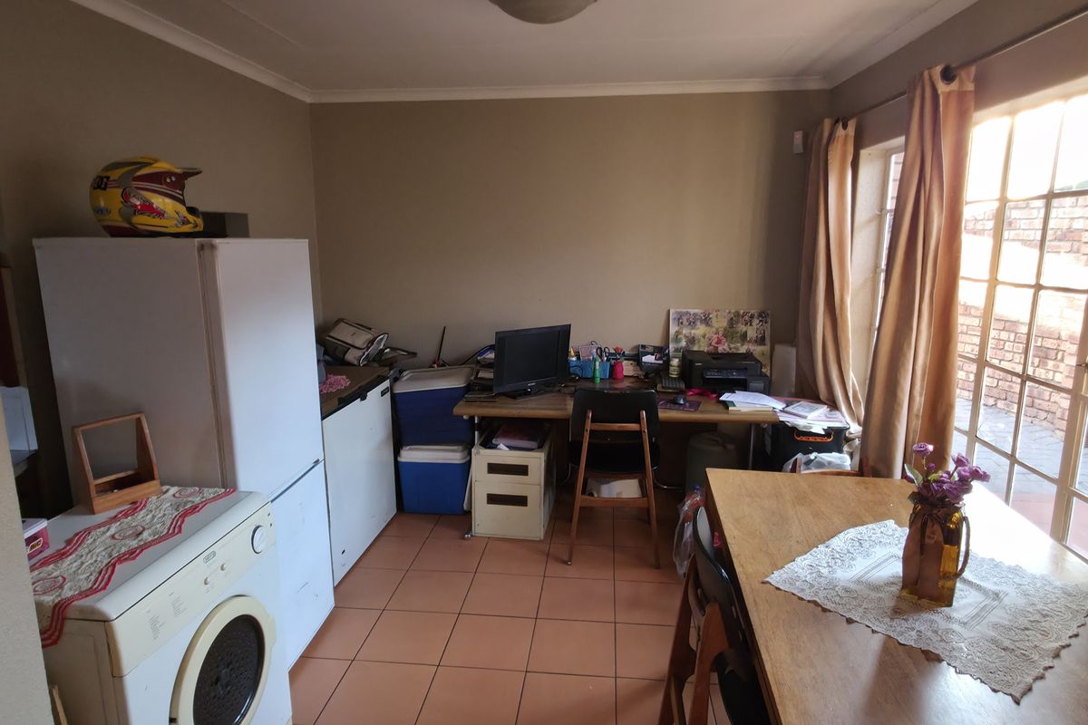 A functional kitchen area featuring tiled flooring and natural light from a large window, offering potential for modernization and improved layout.
