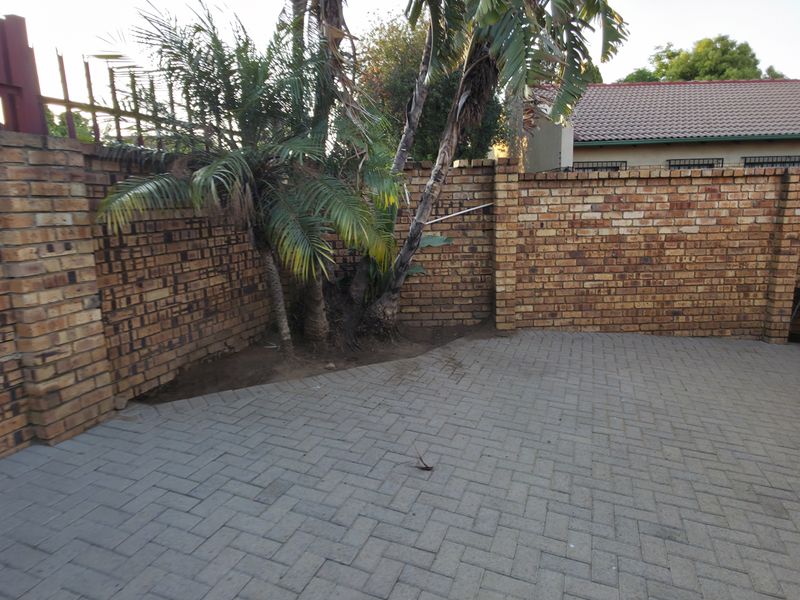 A private rear courtyard featuring paved flooring and high brick boundary walls with security spikes, offering a secure outdoor space.