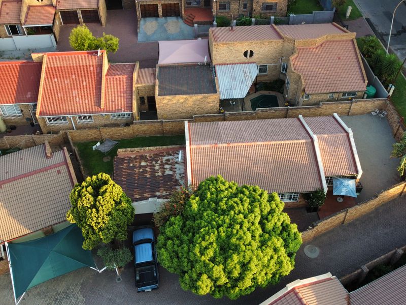Aerial view of the property showing the tiled roof structure, paved driveway, boundary walls, and small swimming pool in the rear courtyard.
