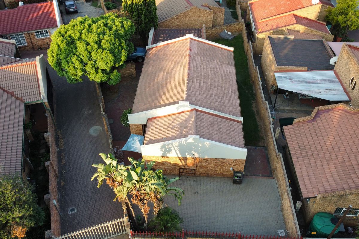 Aerial view of a residential property featuring a tiled roof, facebrick facade, and paved driveway within a secure complex setting.