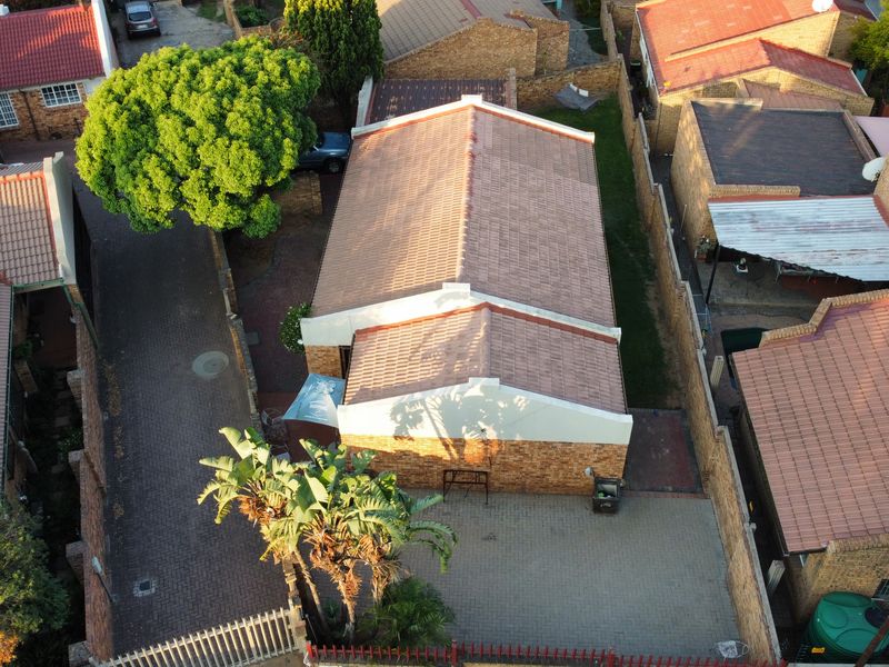 Aerial view of a residential property featuring a tiled roof, facebrick facade, and paved driveway within a secure complex setting.