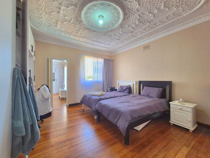 Spacious bedroom featuring original ornate pressed metal ceilings, decorative ceiling rose, and polished timber floorboards, offering a classic architectural character.