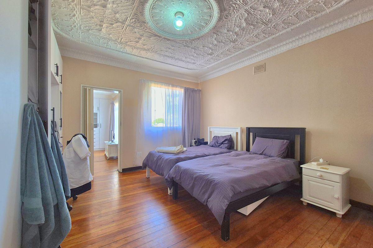 Spacious bedroom featuring original ornate pressed metal ceilings, decorative ceiling rose, and polished timber floorboards, offering a classic architectural character.