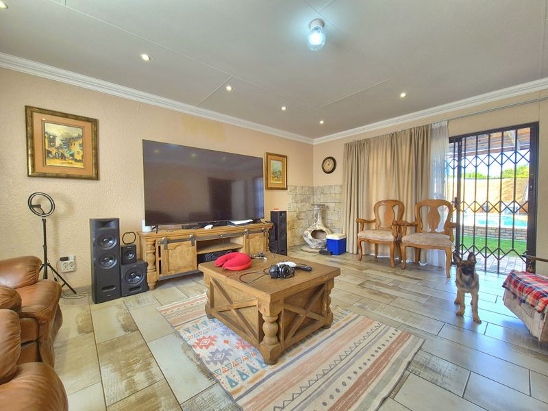 A comfortable living room featuring tiled flooring, recessed lighting, and a stone accent wall, with direct access to the outdoor pool area.