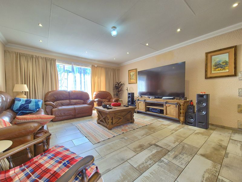 A spacious living room featuring tiled flooring, recessed downlights, and textured wall finishes, providing a comfortable and functional family entertainment area.
